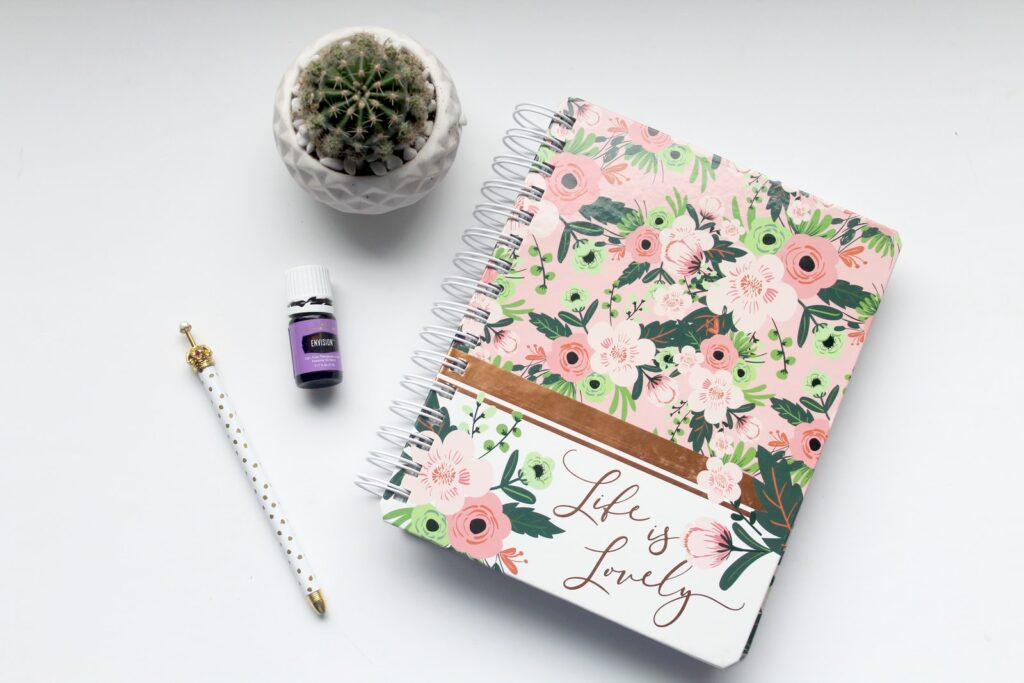 white and pink floral notebook on table