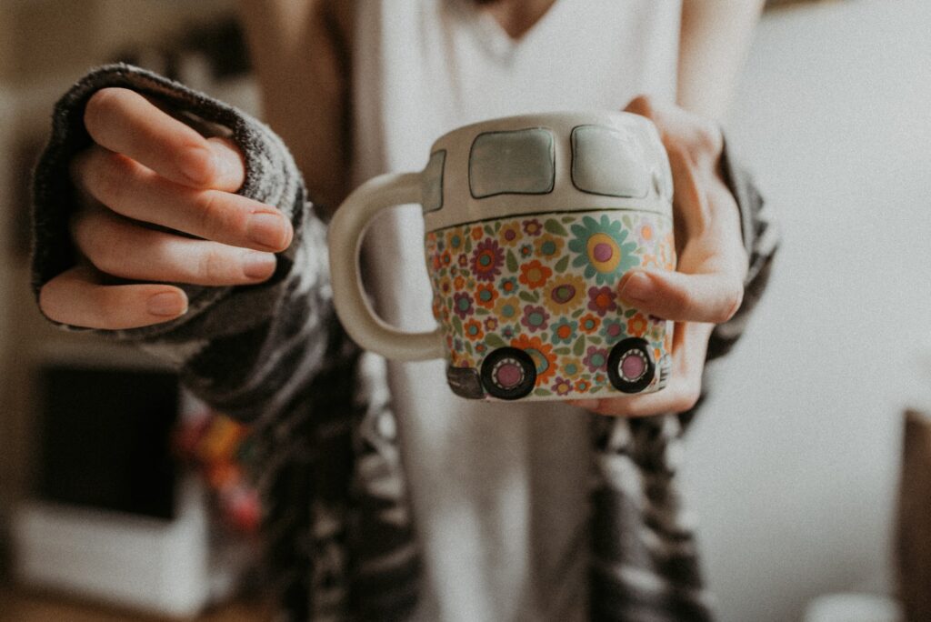 person holding white floral mug