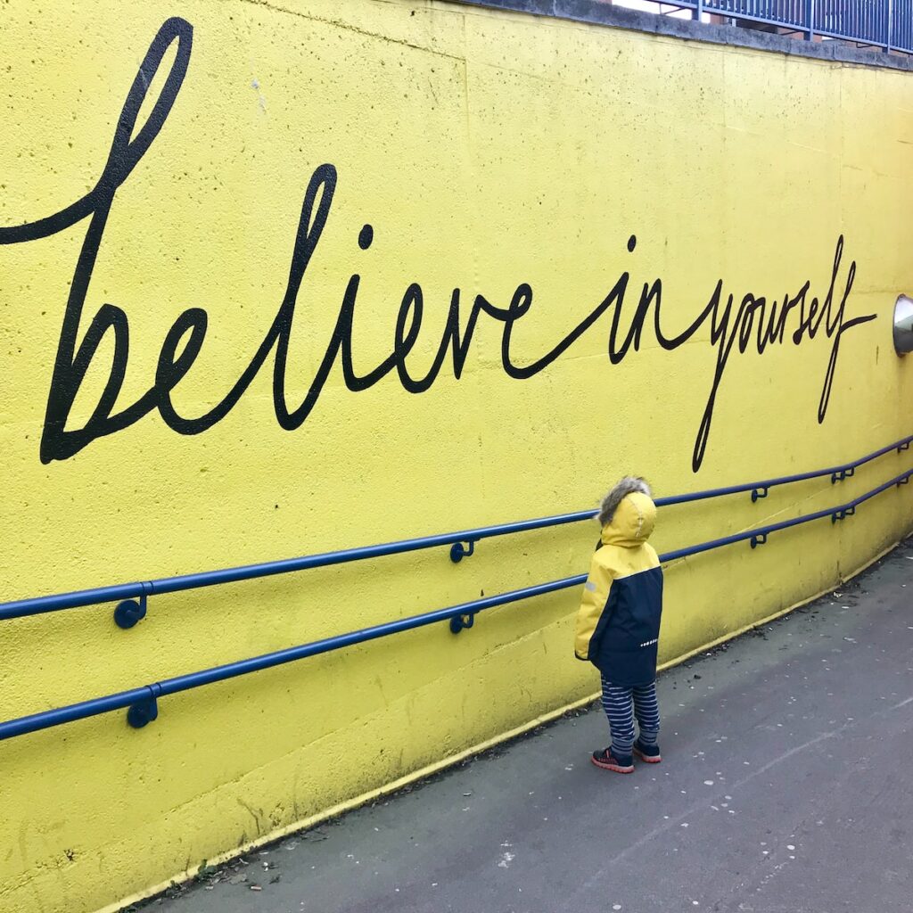 toddler looking at believe in yourself graffiti 