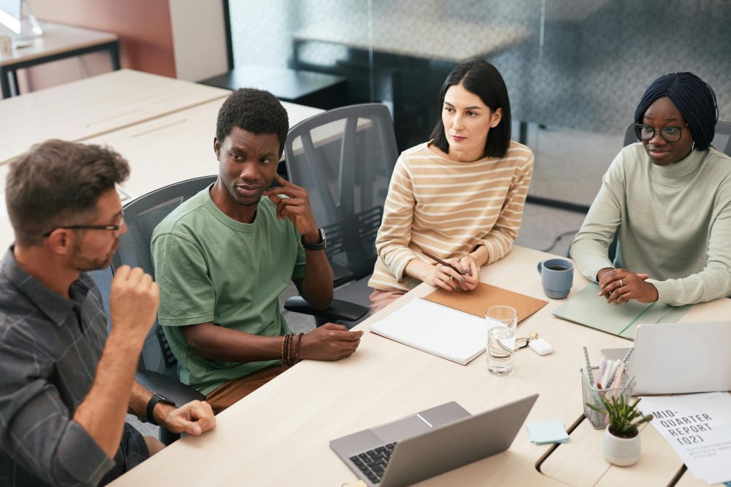 A diverse group of colleagues actively participating in a team meeting inside a modern office.